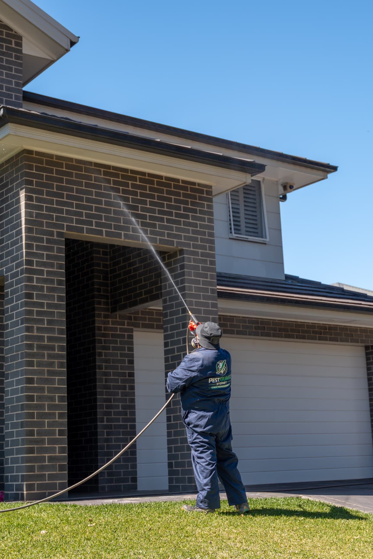 PestGuard technician applying a residual pest spray above the garage pillars and entry points of a Sydney home
